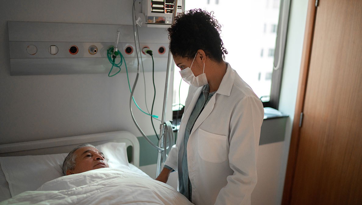 Ärztin spricht mit einem Patient im Krankenhausbett