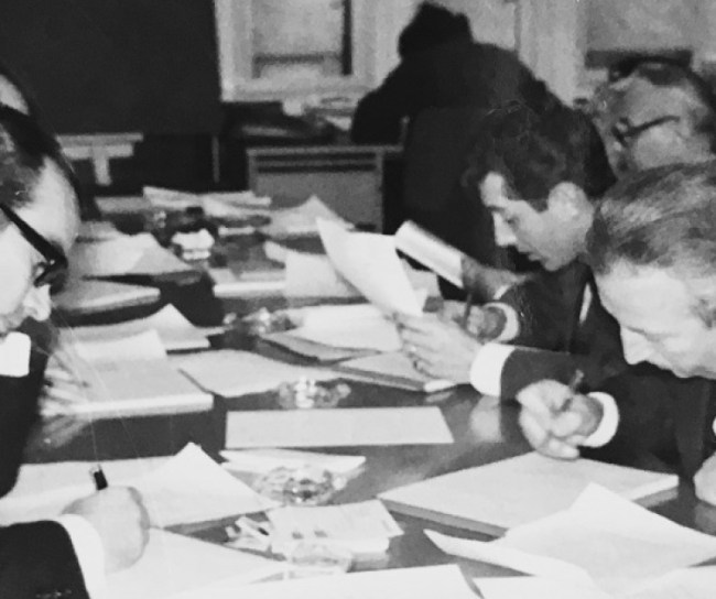 Männer sitzen am Tisch und unterzeichnen Verträge