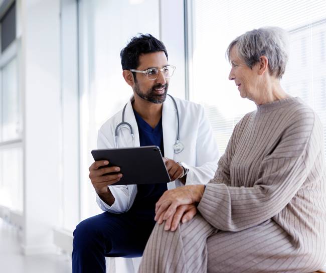 Arzt und Patient im Gespräch, schauen auf ein digitales Tablet