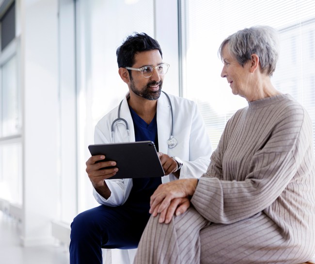 Arzt und Patient im Gespräch, schauen auf ein digitales Tablet