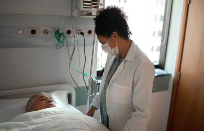 Doctor talking to patient lying in a hospital bed