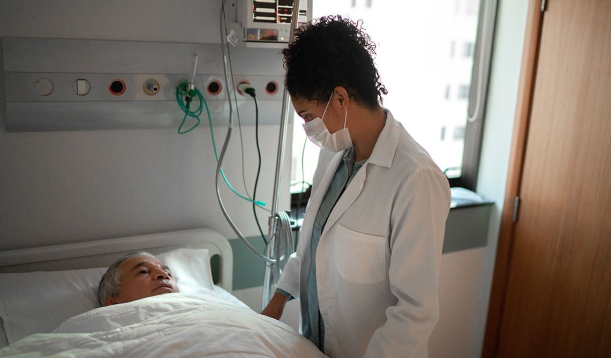 Doctor talking to patient lying in a hospital bed