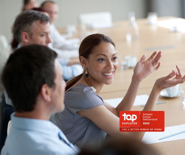 Young woman smiles during a meeting at the table with colleagues.