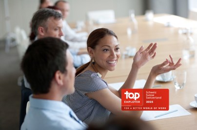 Young woman smiles during a meeting at the table with colleagues.