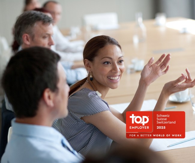 Young woman smiles during a meeting at the table with colleagues.