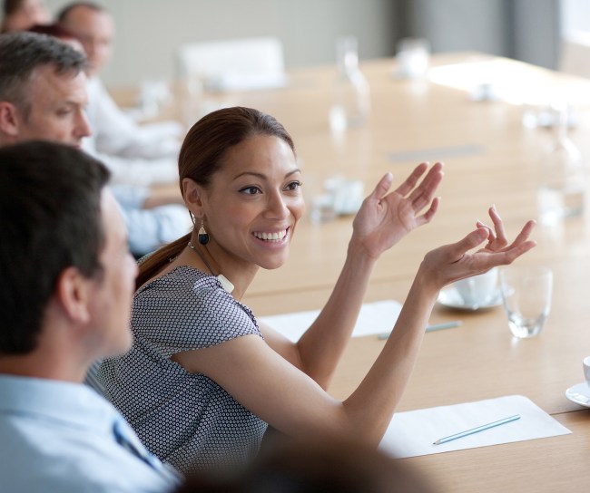 Young woman smiles during a meeting at the table with colleagues.