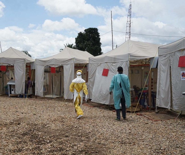 Personnes en vêtements de protection devant des tentes dans la zone Ebola